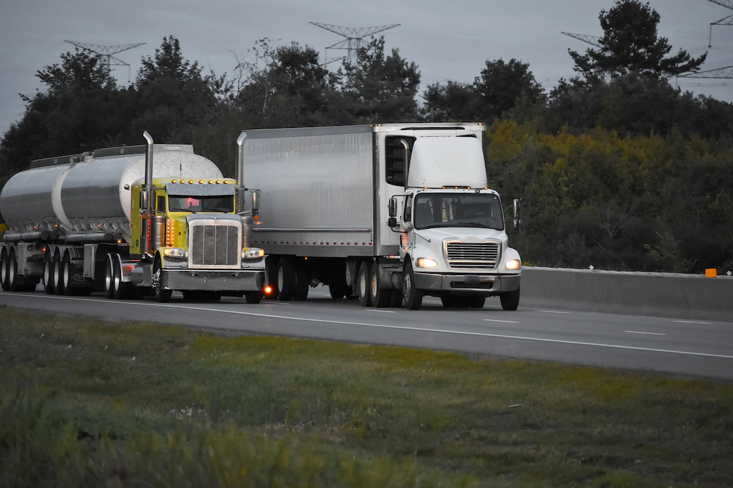 trailer-trucks-driving-road-surrounded-by-beautiful-green-trees_181624-10810